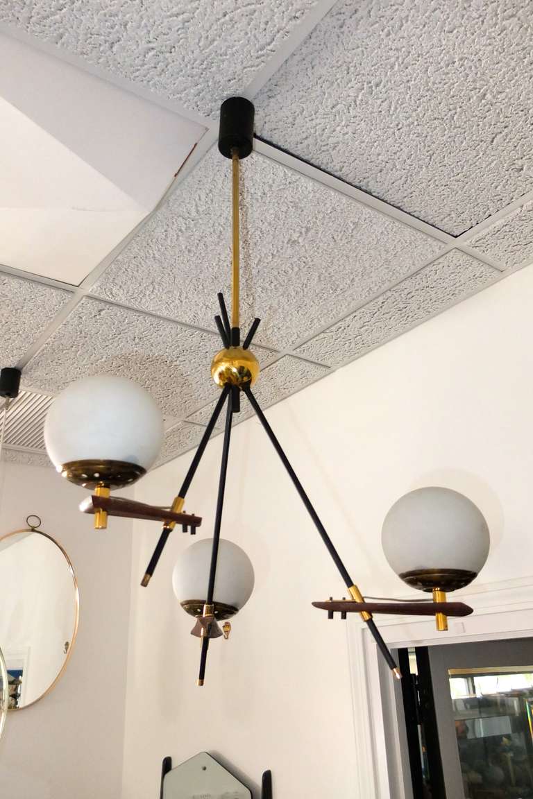 1950s Italian asymmetric three arm chandelier by Stilnovo in sputnik form with three satin opaline glass globes on brass bobeches extending from wedge shaped walnut pieces embellished with brass fittings.