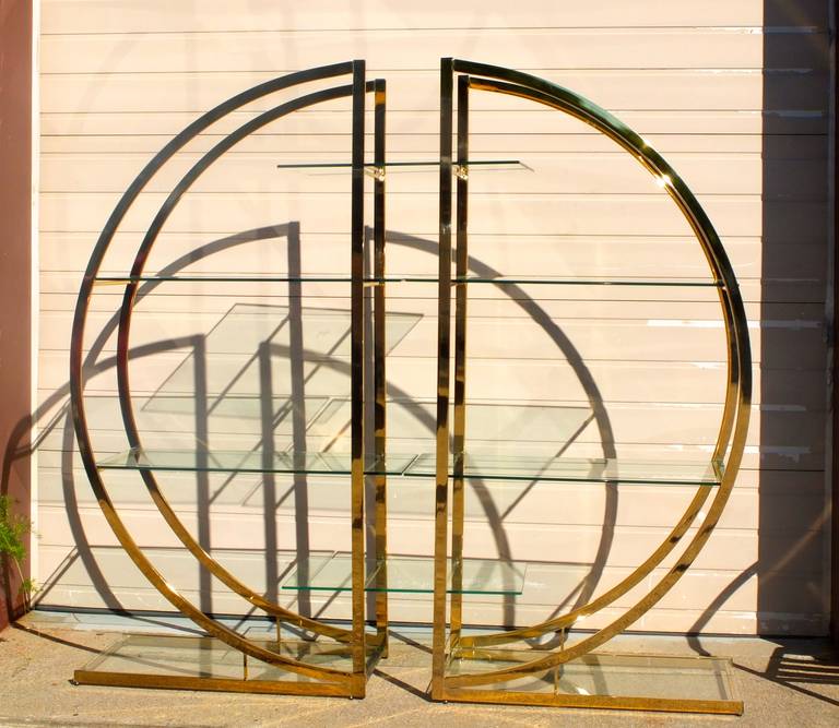 Wonderful pair of semi-circular brass etageres with glass shelves.  Together they make an impressive architectural statement.

Attributed to Milo Baughman for Design Institute of America (DIA)

Original design contemplates two center glass