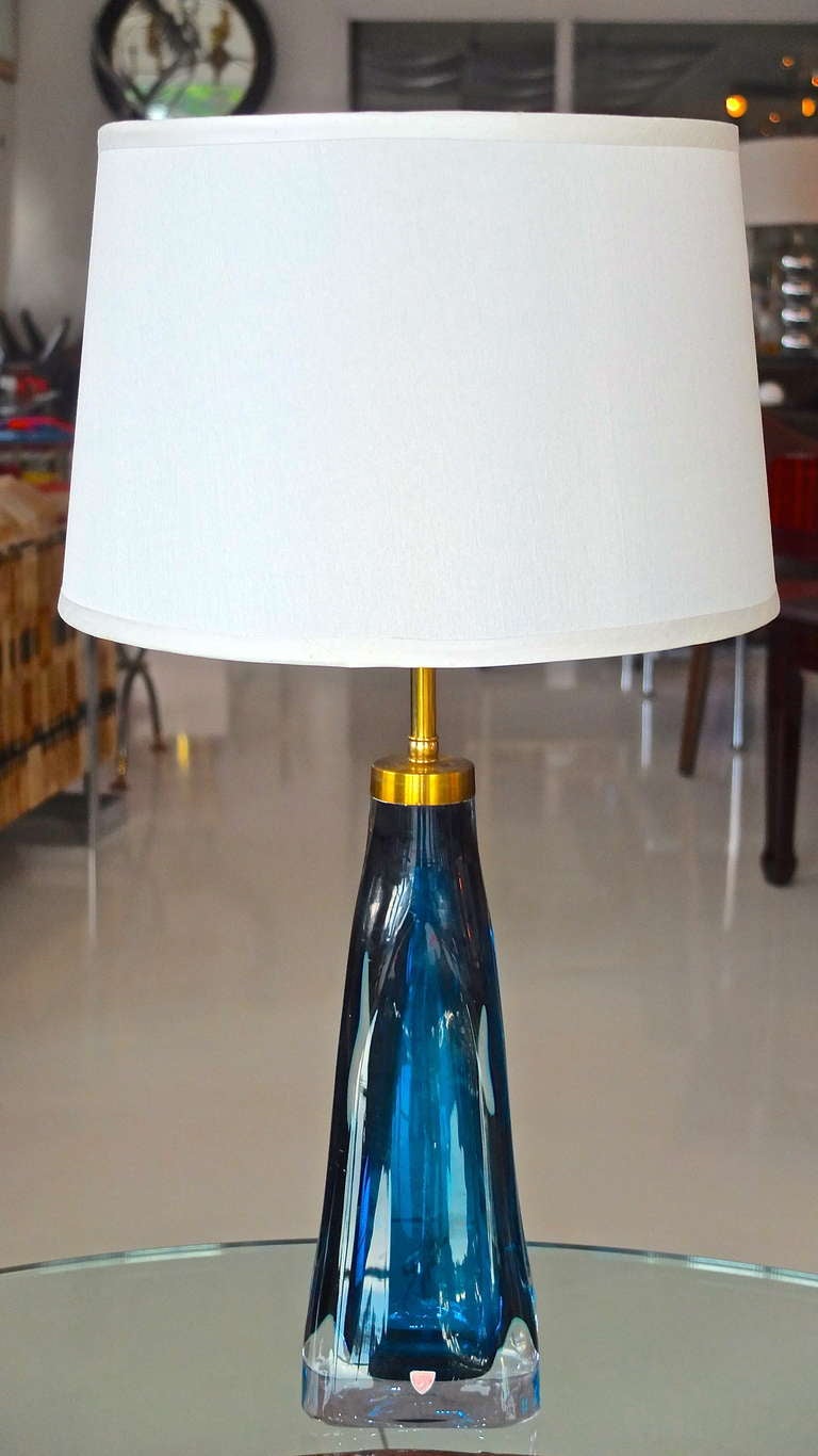 Beautiful blue glass table lamp by Carl Fagerlund for Orrefors, Sweden, circa 1960's with brass fittings. Totally rewired.  Double sockets with pull chains. Adjustable lampshade riser. Glass is signed/engraved on the underside.  Brass cap engraved