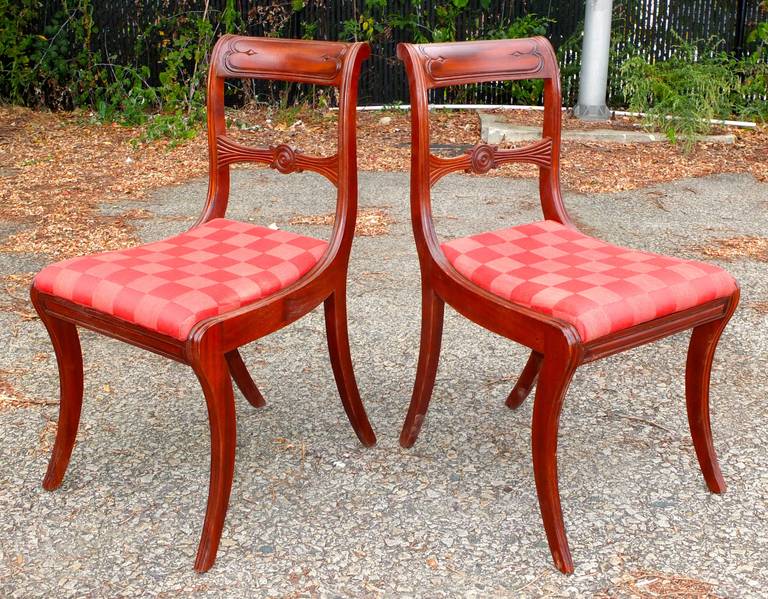 Set of six Regency mahogany dining chairs each with curved back solid toprail above a moulded horizontal splat, above a drop-in seat covered in crimson check, on reed-front saber legs and seat rail.
H33 D 17 W 18 1/2.

See companion Regency