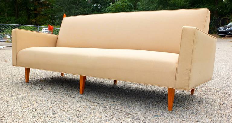 Vintage mid-century modern sofa in the style of Paul McCobb and Dunbar with bench seat, tight back and angled wedge arms on six square tapered wooden legs.