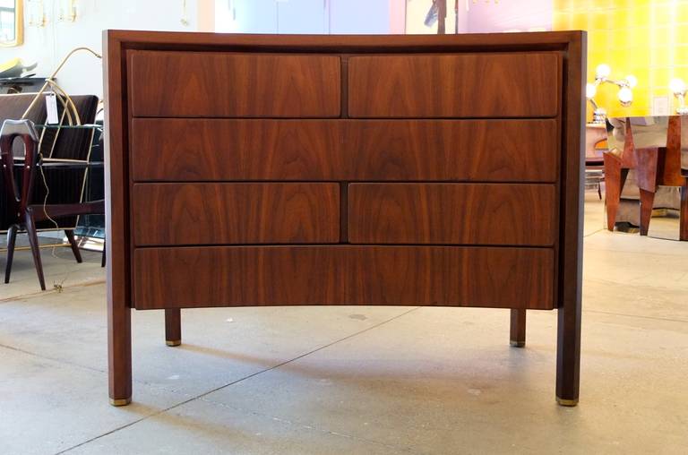 Dark walnut chest on chest by Edmond Spence consisting of a curved front chest of drawers having 6 staggered drawers and hexagonal legs with brass feet, sitting on top of which is a horizontal cabinet having two doors which open to reveal three