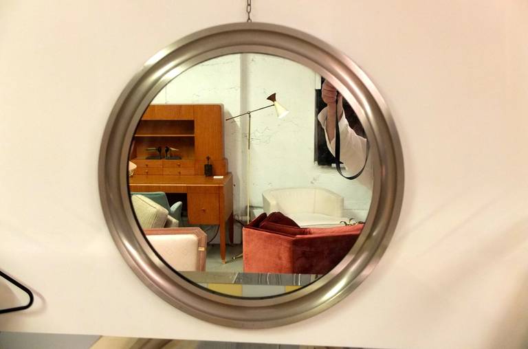 Brushed nickel plated brass mirror by Sergio Mazza for Artemide in 1969. 25 inches in diameter.  Comes with several feet of chain attached to the back so it hangs on the wall as if a pocket watch from a chain.

We also have the slightly smaller