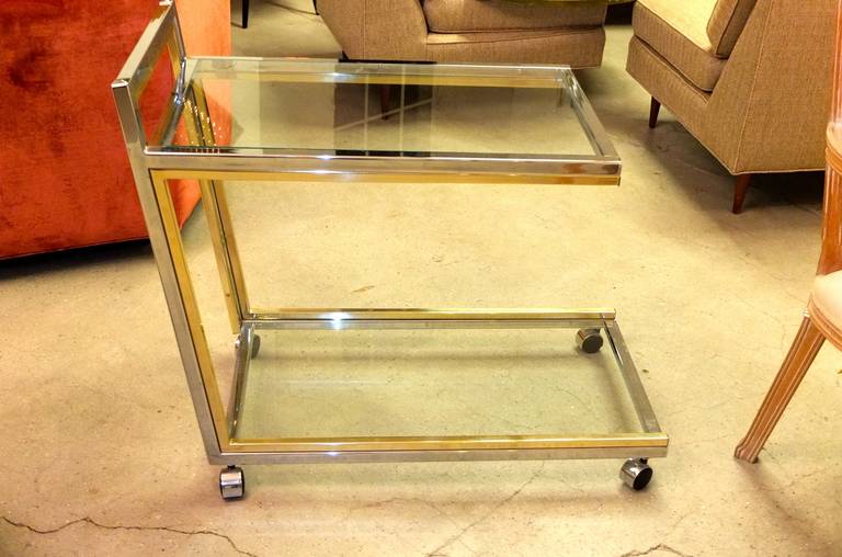This sexy and stylish Italian bar / serving / tea / dessert cart circa late 1960s early 1970s is angled and conveys a sense of fast-forward motion. Perfect original condition.  Two-tone mirror polished brass and chromed steel finish.  Glass shelf