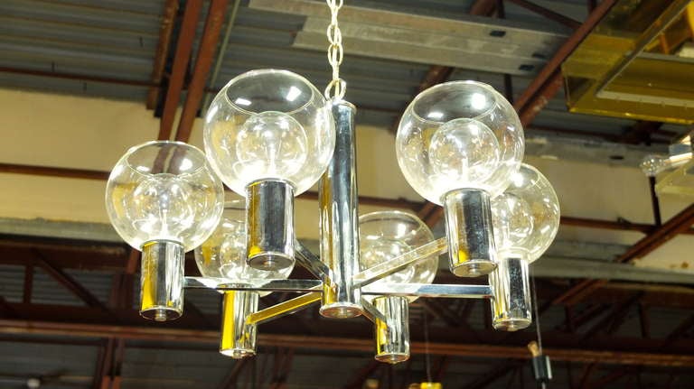 Vintage 1970's modern chandelier in chrome possibly by Lightolier. Six arms extend from a central hub terminating in chrome cylinders  holding large clear glass ball shades with open tops.  Standard Edison screw sockets.  Use with clear glass bulbs