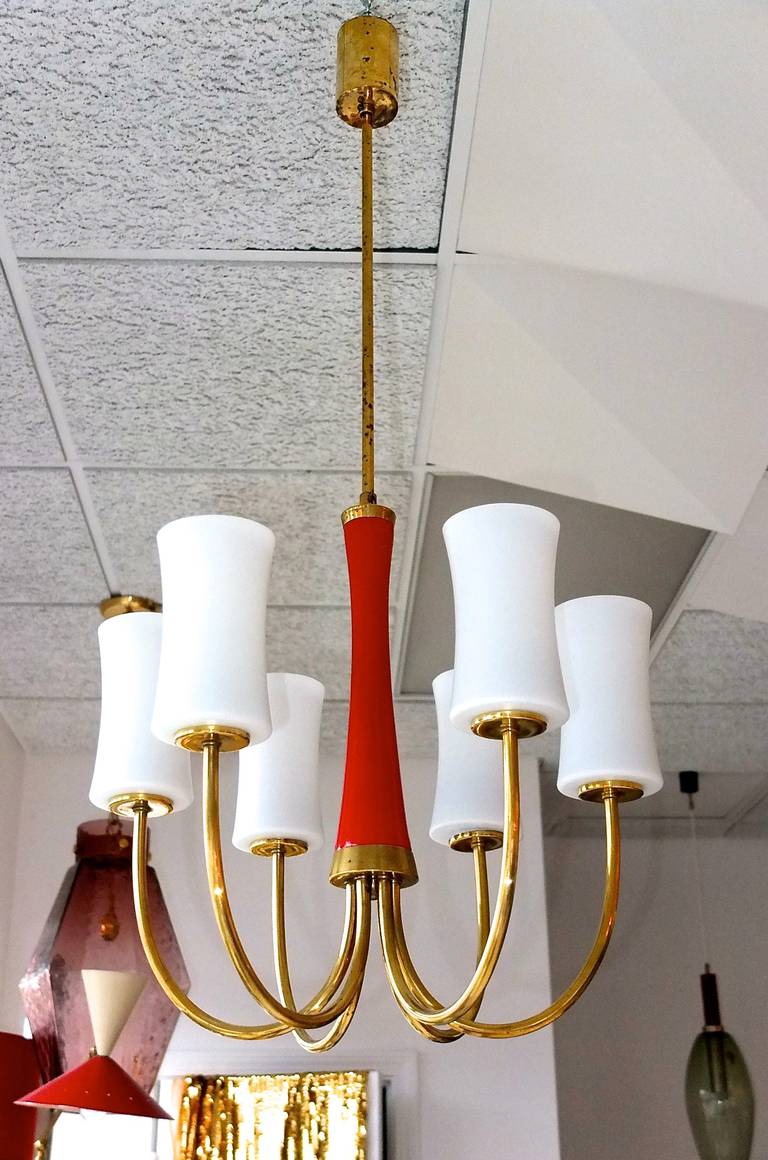 1960s Italian brass chandelier with six brass arms emanating from the bottom of a central elongated hourglass form in enameled red. Even the white opaline shades have tapered waists, to continue the theme, 

Rewired.