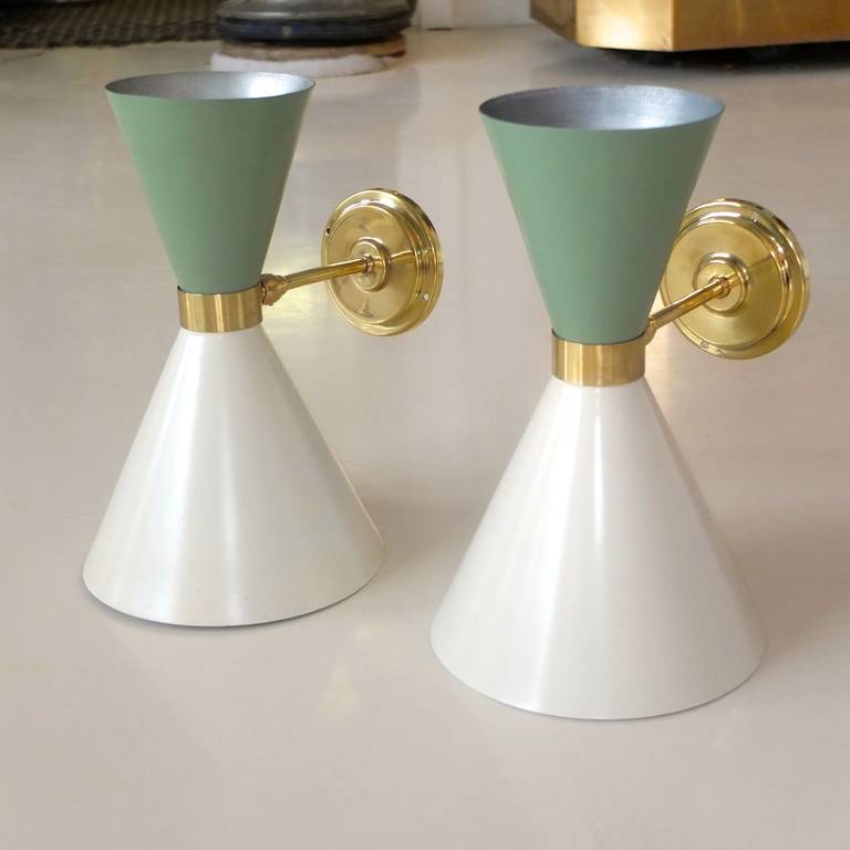 Pair of 1950s Italian double cone sconces in hourglass form with brass collar and swivel joint connecting to a brass rod projecting from the round backplate.
These are similar in style to designs by Stilnovo but these are unmarked. The top cone is