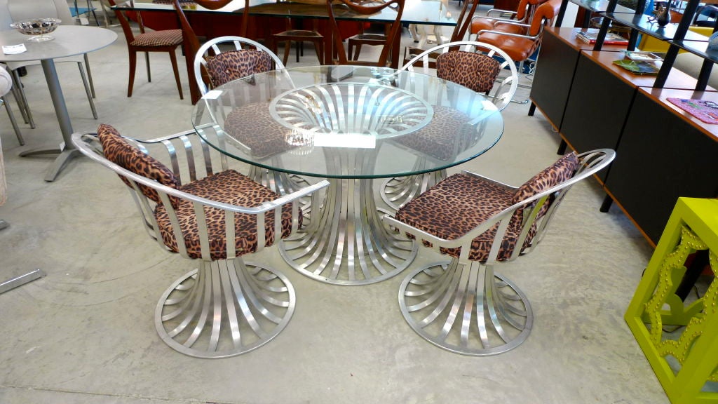 Designed by Russell Woodard and produced in the early 1960's by the Woodard Furniture Company.  Slatted extruded aluminum pedestal base table and four chairs (2 side, 2 arm).  For indoor and outdoor use depending upon cushion covers.
