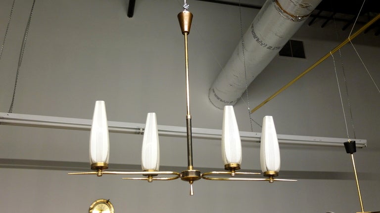 French 1950's modernist chandelier of sleek design. Four square edged flared tulip white glass shades sit in round brass bobeche on two horizontal curved brass sharply pointed arms.  Drop rod has gun metal finished embelishment.  Original canopy.
