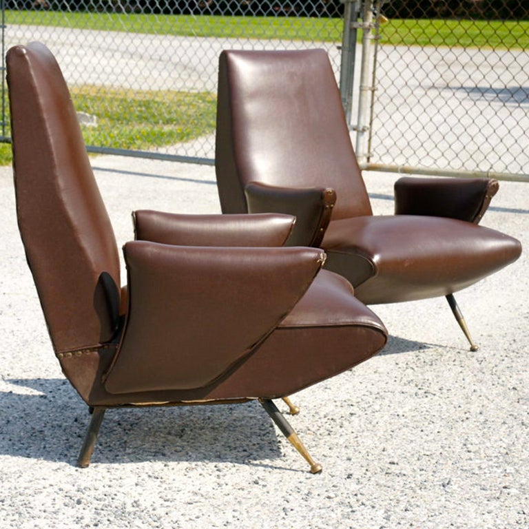 ***September Sale***

Published pair of  1950's Italian lounge chairs by Nino Zoncada for Framar in original dark brown skai (faux leather) upholstery, sculpted side arms and standing jauntily on tapered black enameled steel legs with brass feet