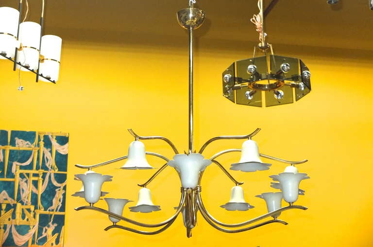 Twelve-arm brass chandelier in the style of Angelo Lelli for Arredoluce with original ivory enameled aluminum scallop-edged cones in the form of lilies of the valley, half oriented upwards, half downwards. Each cup has a single standard size Edison