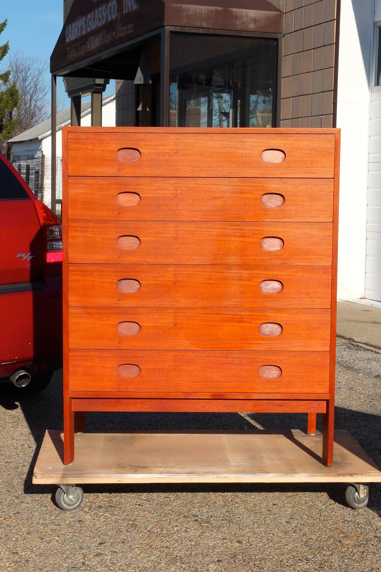Classic mid-century modern Danish tall chest of drawers on stand with trapezoidal legs and inset drawer pulls.  Six drawers.  Top drawer with dividers.