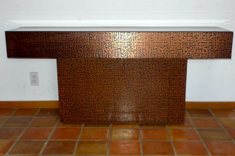 Vintage 1970's block pedestal console table clad in embossed copper metallic laminate, the embossing cavities in black against the copper color relief, in the pattern of a circuit board or or 1960's 'Sci-Fi' typeface..  Finished on both sides for