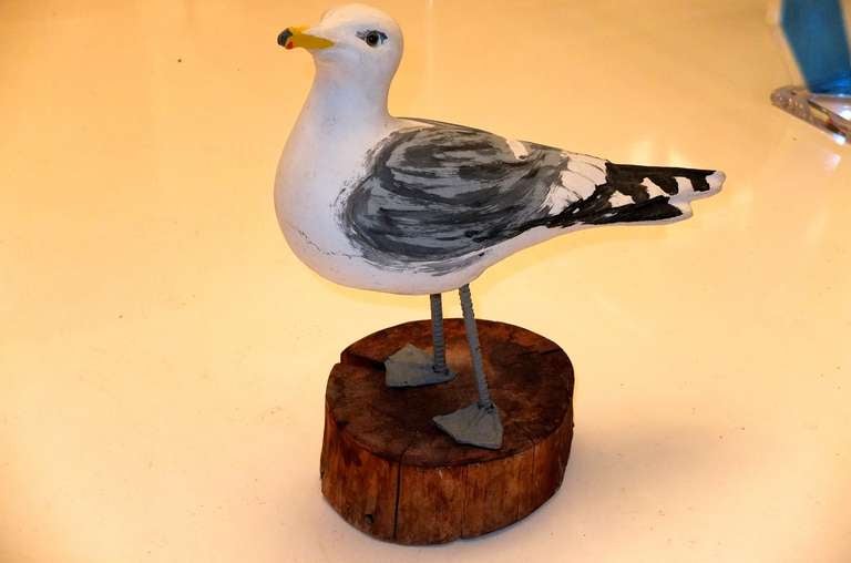 Life size and realistic hand painted seagull made of concrete on iron legs with lead webbed feet on beach wood pedestal stand.

It is signed and numbered on the underside but I cannot quite make out the name.  It looks to me like CAROHN or CAROLN