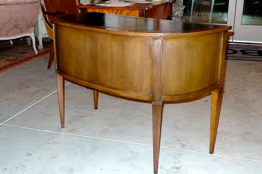 This demi-lune desk has classic directoire lines, tapered legs and a tooled leather top.  The wood is Pecan.  The drawers are clean and slide smoothly.

This desk is freestanding and can be presented in the round.