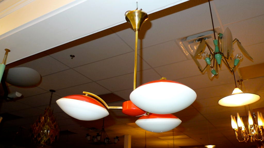 Unusual space age chandelier by Phillips of the Netherlands.  Three brass arms radiate from a red enameled aluminum center with three saucer / dome shaped lights.  Red enameled crowns and white satin glass reflectors.