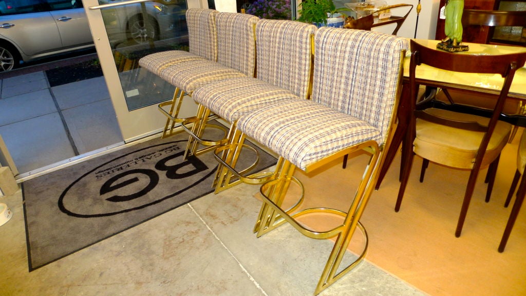 Set of four bar-height stools from the early 1980's  in bright shiny brass, produced by DIA and attributed to Milo Baughman.  The cantilevered flat bar style frame give these a very bold and striking appearance.

Price is for the set of