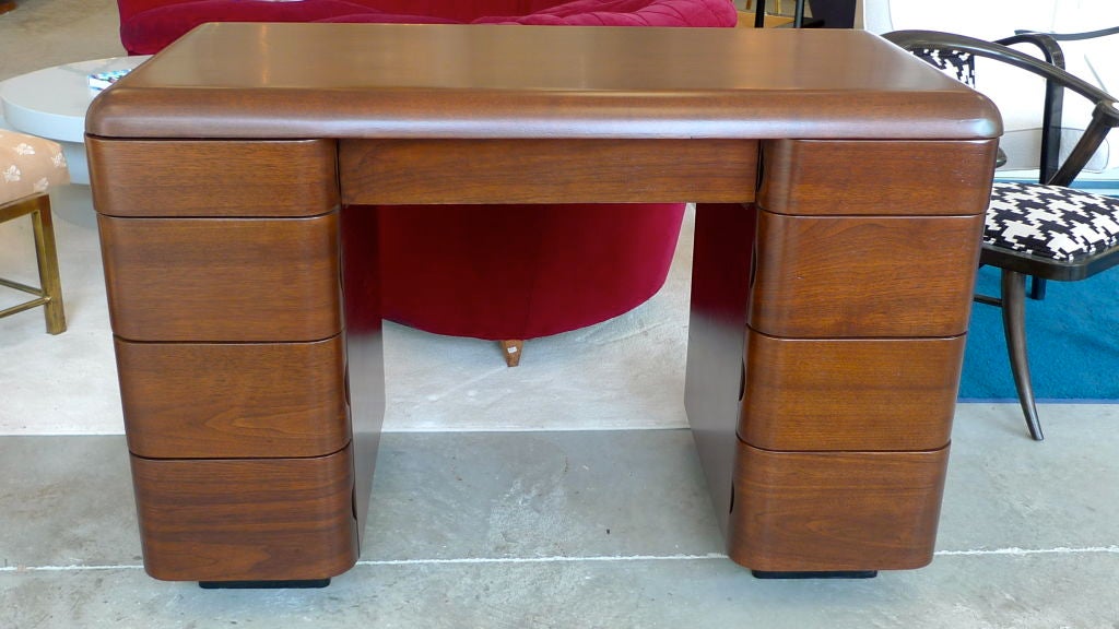 A piece of Massachusetts manufacturing history, this is an early work by Paul Goldman for Plymold Corp of Lawrence, MA circa 1945.  Constructed of bent plywood with the art deco stylings of a tanker desk; note the rounded edges (on both front and