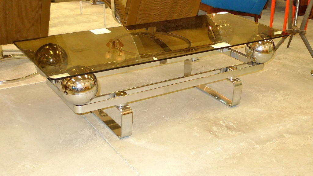 Vintage early 1970's chromed flat-bar steel coffee table from France.  The original smoked glass top floats on four large chromed orbs. Evocative of the designs of Maria Pergay.