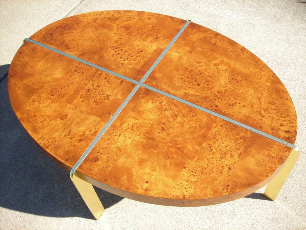 Arrestingly handsome large oval cocktail table by Milo Baughman in olive burl with a brass frame which on the top appears as inlay and then emerges as rounded edge scaffold-like legs.  Masculine, understated elegance.