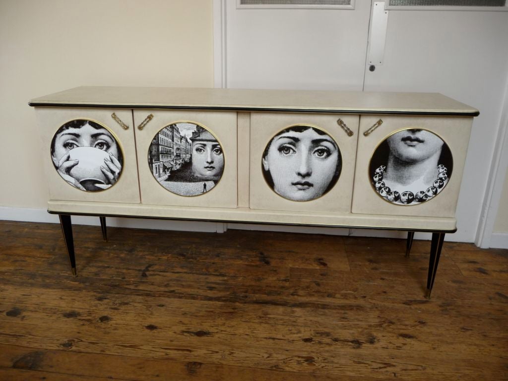Six foot sideboard buffet designed by Umberto Mascagni of Bologna and retailed at Harrod's.  Case legs and doors covered in snow white skai.  Original glass top.  Laminated Fornasetti panels are a later embelishment.<br />
<br />
Legs remove for