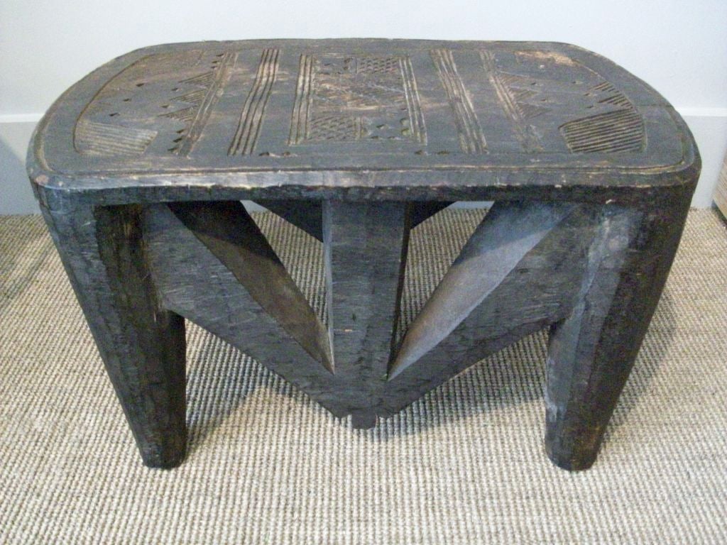 This 4 legged Nupe Stool is carved from one block of wood and has an abstract, geometric pattern carved in the top.  These stools were used by everyone in the tribe - but this larger size would have been made for an important person like a Chief or