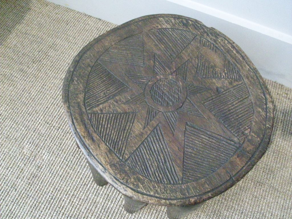 The Nupe Peolple carved these stools from one piece of wood.  This one has 10 tapering legs. (a couple of the legs do not touch the ground) The top is carved with a geometric star shaped pattern.