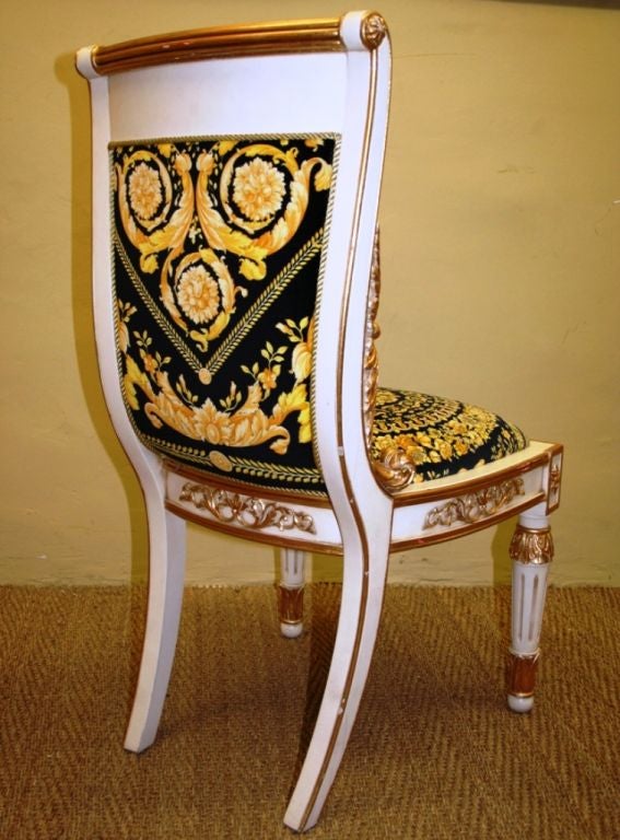Amazing pair of Neo Classical chairs from Gianni Versace.<br />
Golden leaf and lacqued wood. Sword shaped back legs and Empire front as in the pure classical tradition.The back opens wider and goes down in curved lines down to the seat,in a