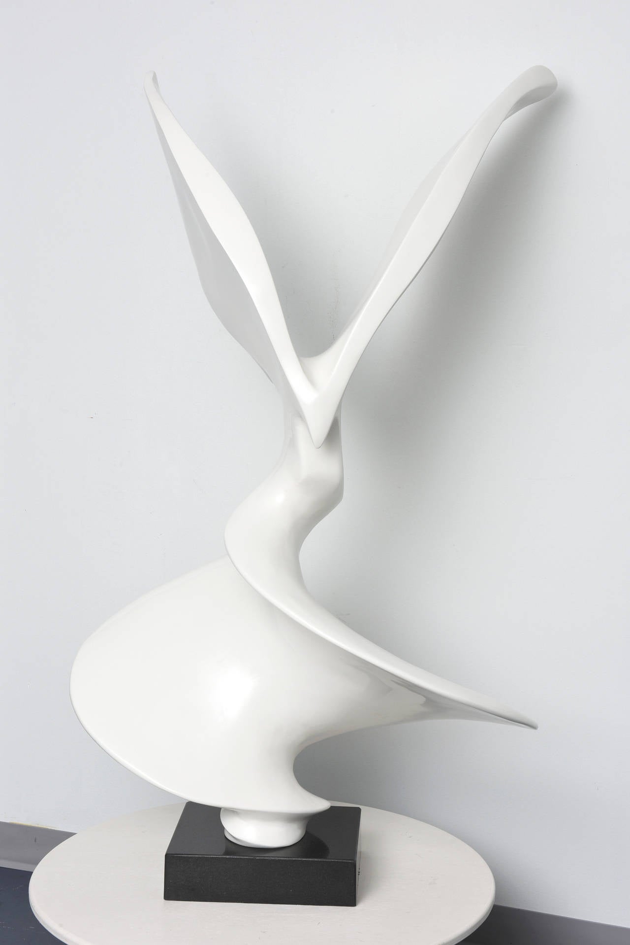 An abstract shape of a flying bird. The sculpture is attached to a black marble pedestal.