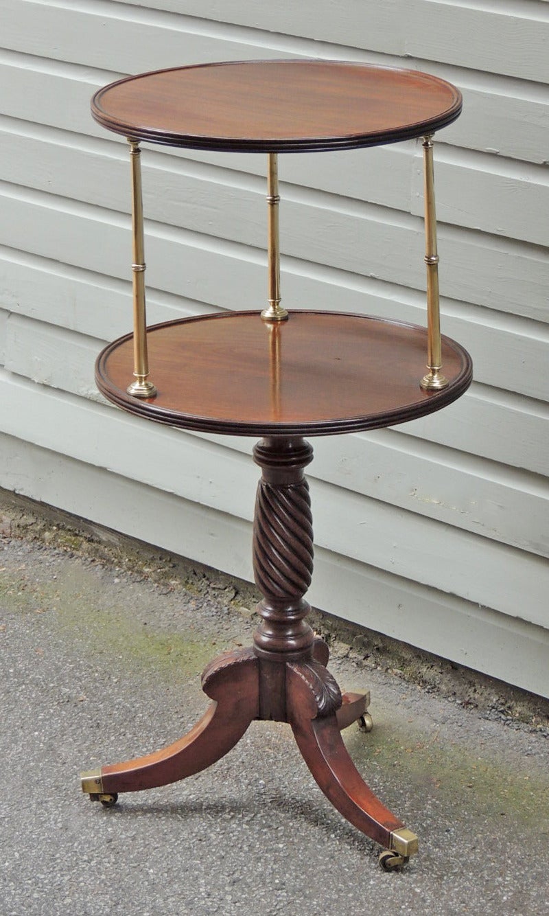 This dumbwaiter was made in England during the late-18th century to early-19th century, circa 1790. This piece is made of solid Cuban mahogany and features a traditional double surface with reeded edges separated by three brass columns. The turned