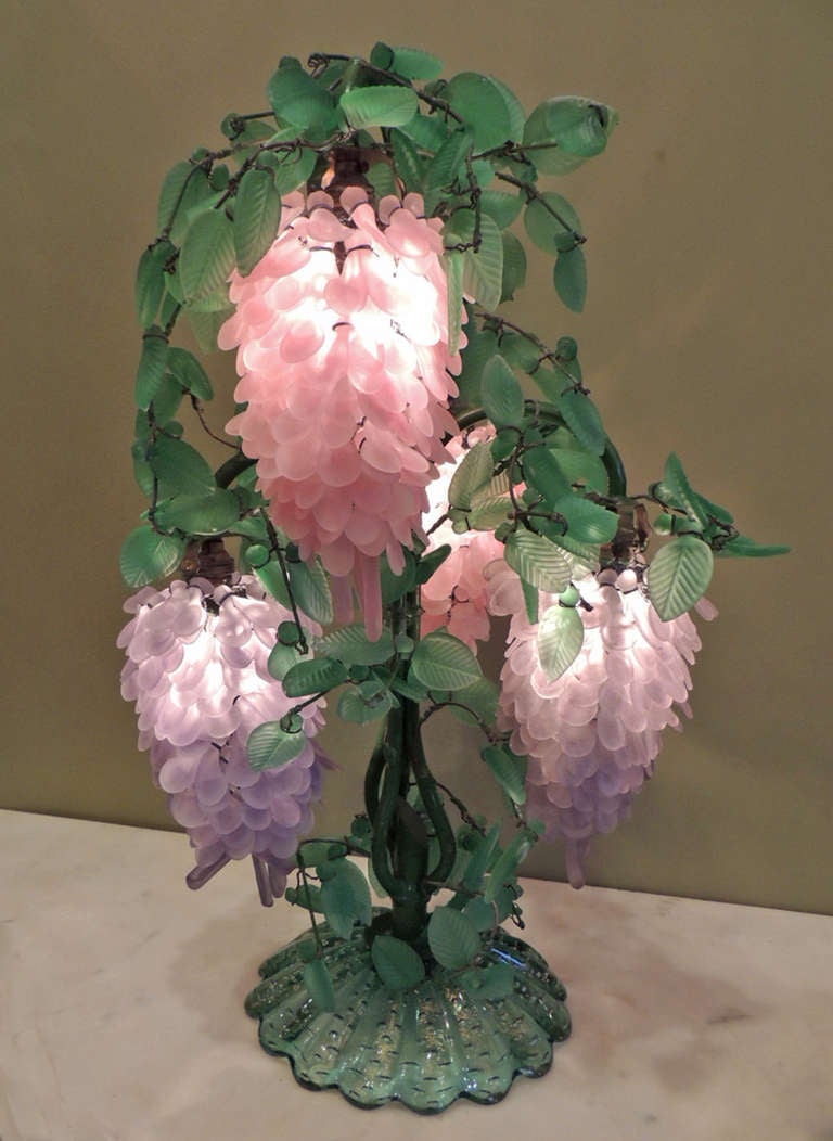 This pair of lamps were made of green, pink, and purple colored glass and is meant to resemble wisteria. The lamps are made with handmade glass from the Italian island of Murano and have recently been rewired.