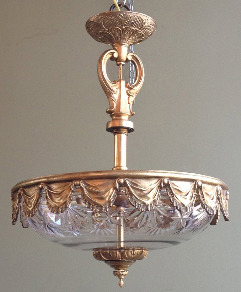 This is an early-20th century French chandelier that features patterned crystal and bronze doré in draped swags. Recently refurbished and rewired.