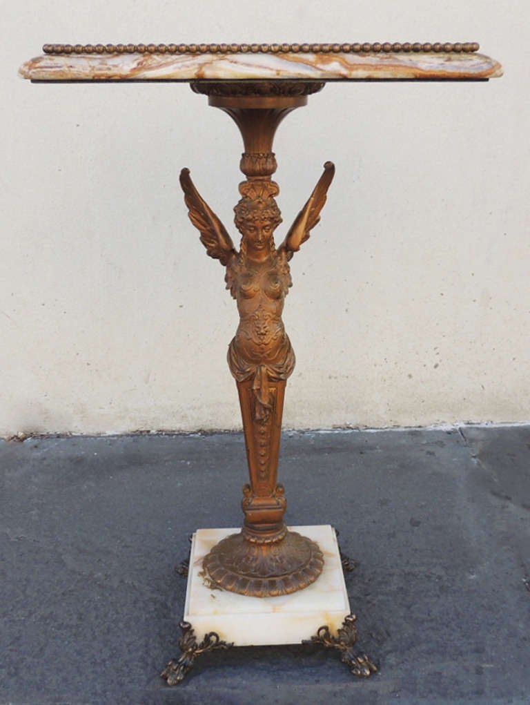 This beautiful piece has a marble and onyx top with a bronze base. The marble top has a beaded onyx border and screws into the bottom half of the stand. The middle section of the stand features a carved angelic figure that is in a Egyptian type