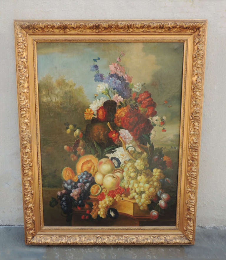 This painting was made in the mid 17th century in the Netherlands and is a still life scene of assorted fruits and flowers. The original gilt frame features carved detailing with a beaded edge. The frame measures thirty-seven inches high by