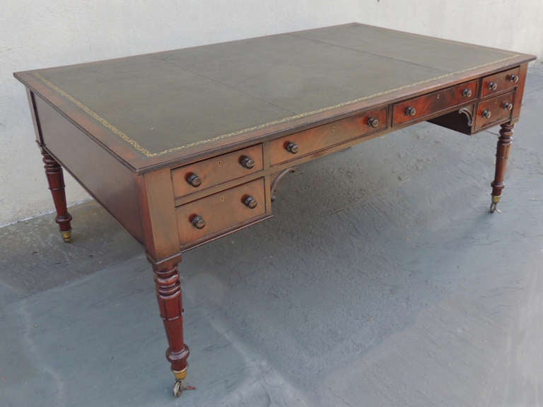This piece is made of mahogany with a gilt-tooled leather top. The secondary woods are pine, dil, and chestnut. There are six drawers on each side with working locks. The tulip legs of this piece have hand-turned top sections, and it sits on its