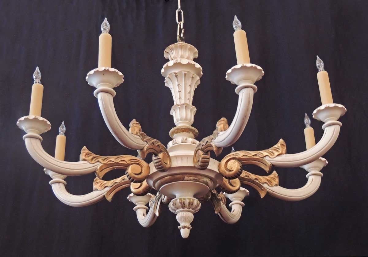 This wooden Italian-made chandelier has been recently rewired and features lovely foliate and scrolling details on its main stem and eight arms.  The chandeliers are painted a cream color with gold accents.