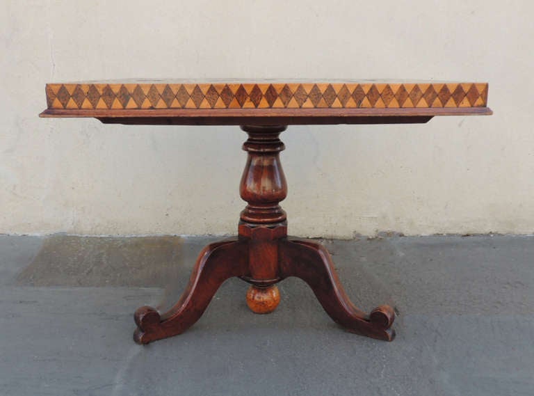 This beautiful West Indies game table was made in the Caribbean during the 1840's. This piece has a tilt top with a tripod base. The base of this piece is made of mahogany and cedrela. The specimen top is made of palm, satin, and ebony wood.
