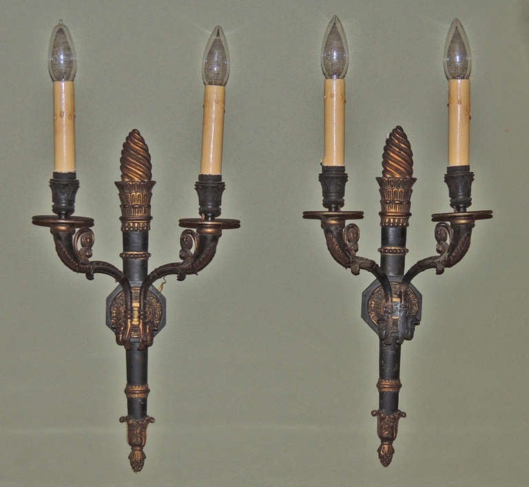 These French sconces are made of patinated bronze doré and were constructed in 1850. The pair was originally gas-burning but has been converted to electricity. The bodies of these sconces resemble flaming torches and feature Egyptian motifs.