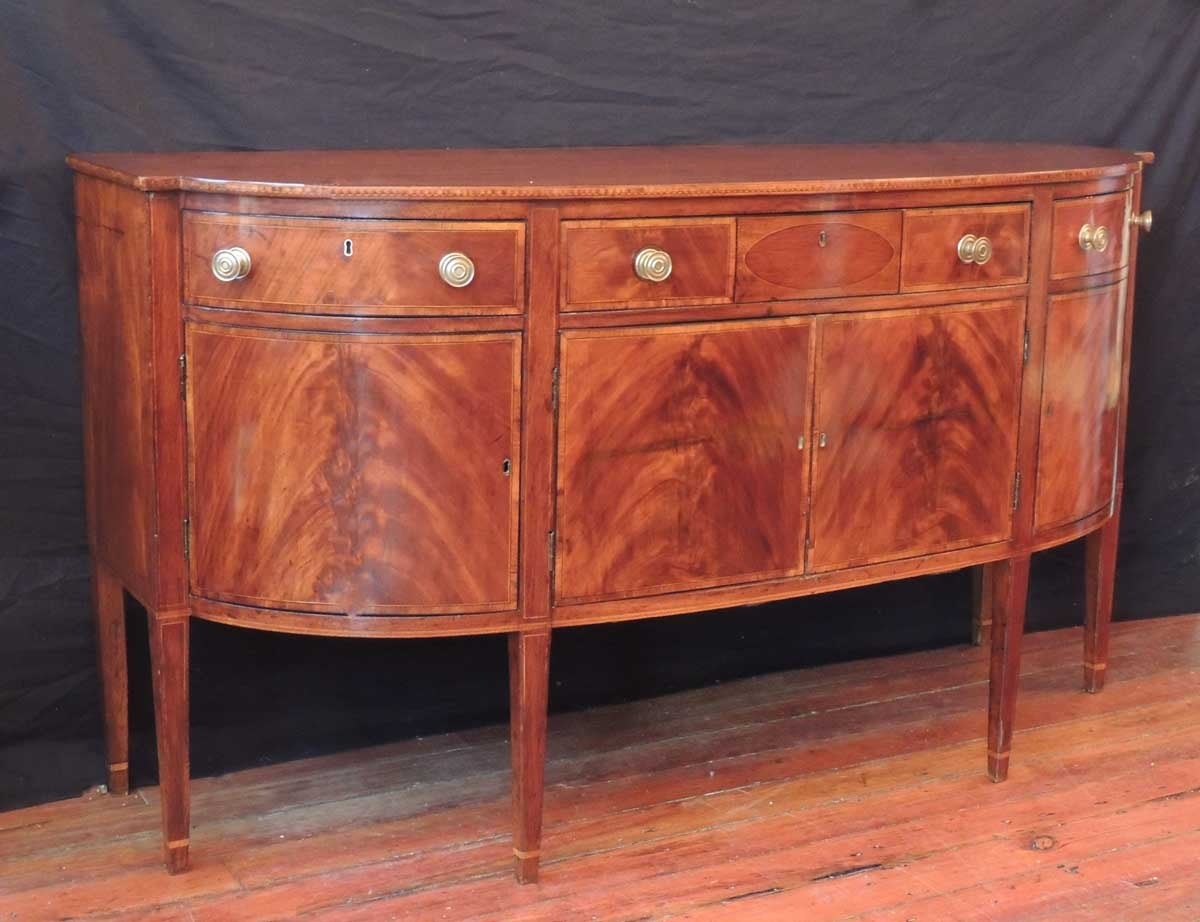 This sideboard was made in Virginia during the late-18th century, circa 1790. This sideboard features three center drawers with circle inlay and two long drawers on each side each with circular brass handles that sit above four square doors. The
