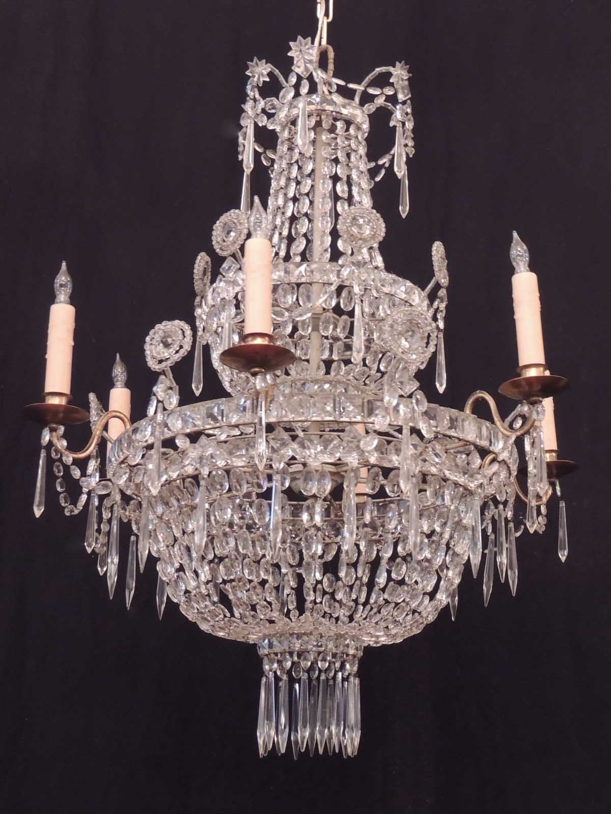 This English Regency crystal chandelier is a spectacular piece.  The body of the chandelier supports two tiers of crystal swag baskets and six candle arms.  The piece is resplendent with crystal swags, drops, and rosettes.  It has been recently