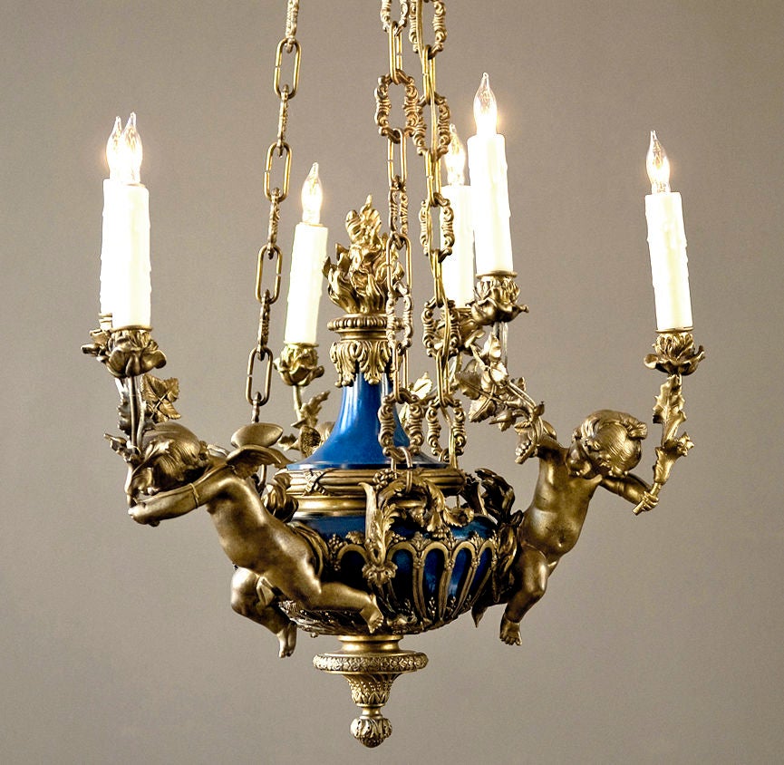 An excellent quality blue enamel and bronze chandelier, originally gas. Each putto holds two candle arms with floral candlecups. An ornate bronze flame adorns the center.