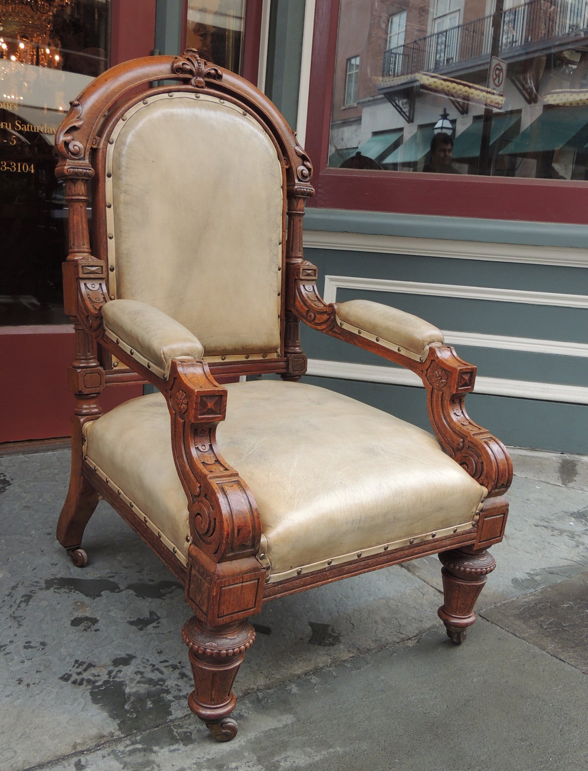 This pair of chairs were made in England, circa 1840. The chairs are made of solid oak and feature intricate carvings on all sides. The arms of the chairs have upholstered padding and unique carved details. The legs have their original casters with