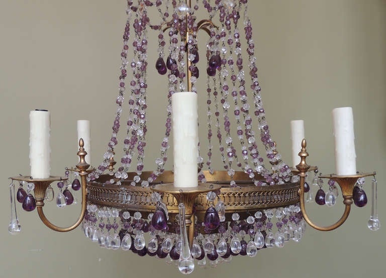 A 20th century six-arm Italian chandelier with amethyst colored and clear crystal swags. The base of the fixture consists of three tiers of amethyst and clear crystal prisms hanging from a punched brass body.