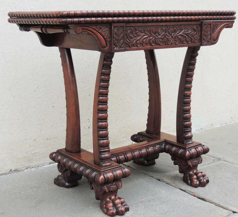 A wonderfully carved mahogany card table. This piece is Bajan, and  features beautiful paw feet, carved legs, and a lovely carved foliage motif on the top. Two handles on either side. A rotating top, and folding card table aces this piece especially