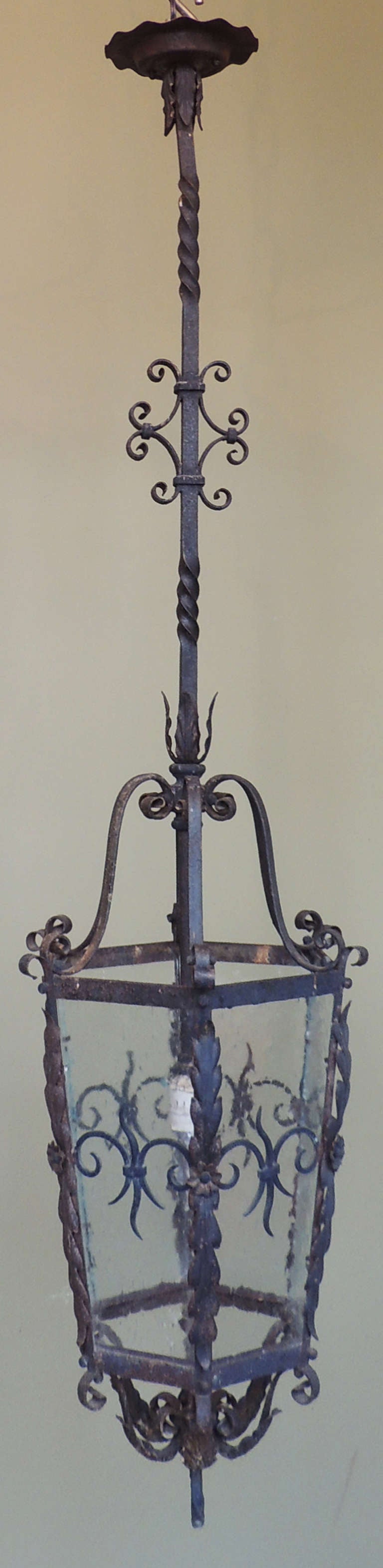 This French Gothic wrought iron lantern, circa 1870, features hand-wrought iron with scroll and foliate designs and glass panels. The lantern was originally gas but has been recently rewired with new sockets.
