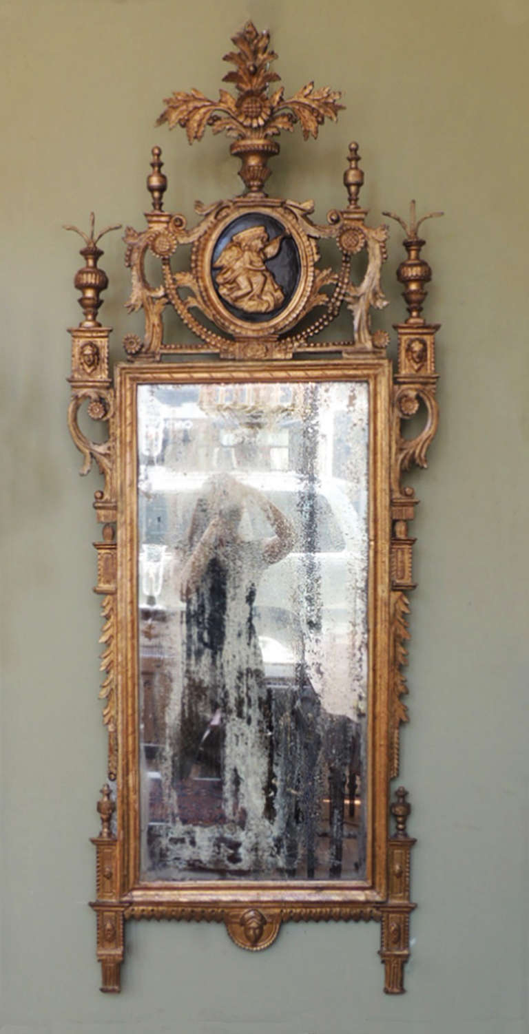 This exquisite mirror was made in Tuscany, Italy, in the late-18th century, circa 1790. The frame is carved wood with its original plate and mirror. The top of this piece features floral arrangements in urns with beaded and foliate decoration. In