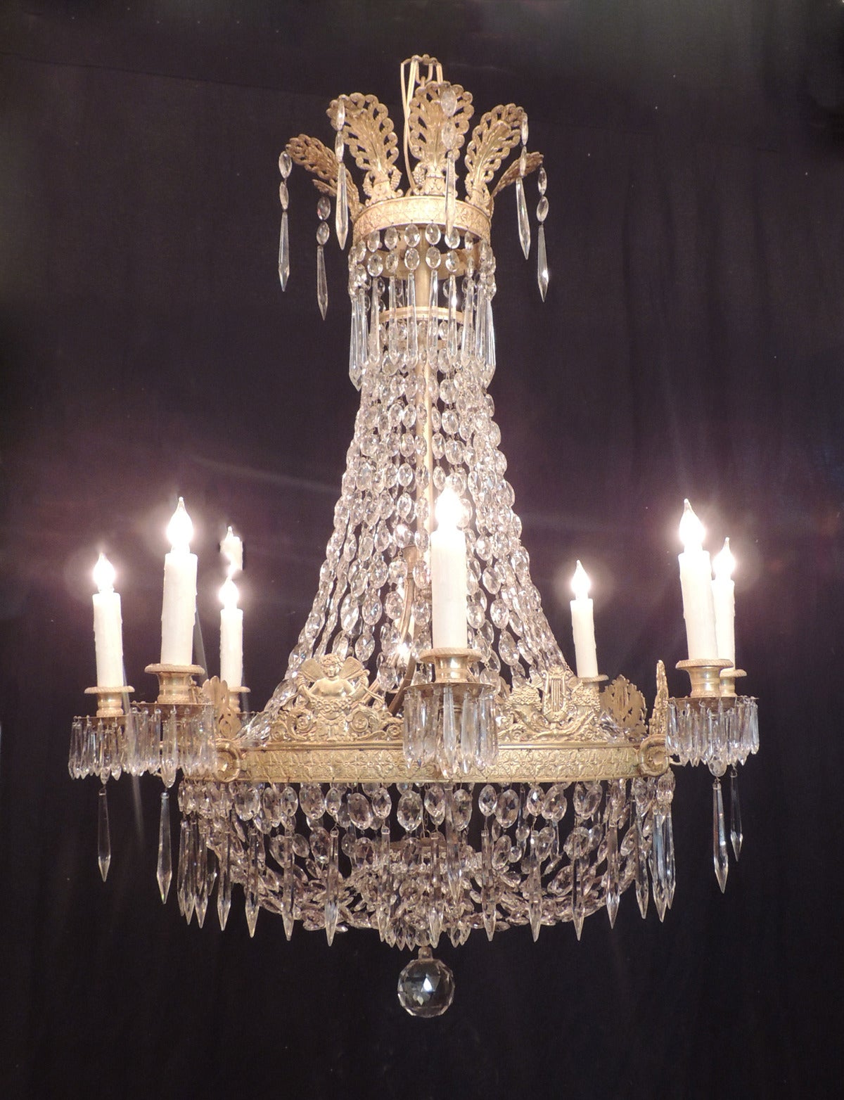 This chandelier was made in France during the first half of the 19th century, circa 1800. This piece is a traditional basket-style chandelier with an anthemion crown and crystal beading attaching to the body of the piece.  The center border is cast