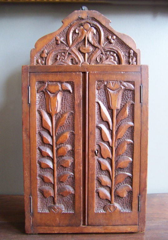 A charming and decorative Pennsylvania Dutch two door hanging spice cabinet. Chip carved decorative elements include tulips and love birds typical of Pennsylvania Dutch folk art. High quality attractive piece.