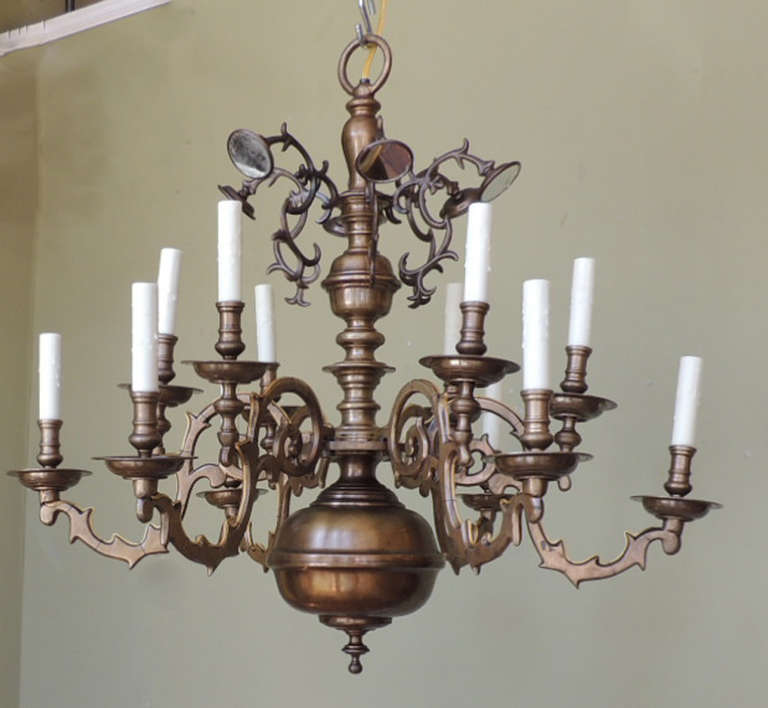 This chandelier was made in the Netherlands during the mid 19th Century and is constructed of Brass. The top of this piece features vignette type arms with mirrored reflector to allow for more light to come into the room. The long and slender body