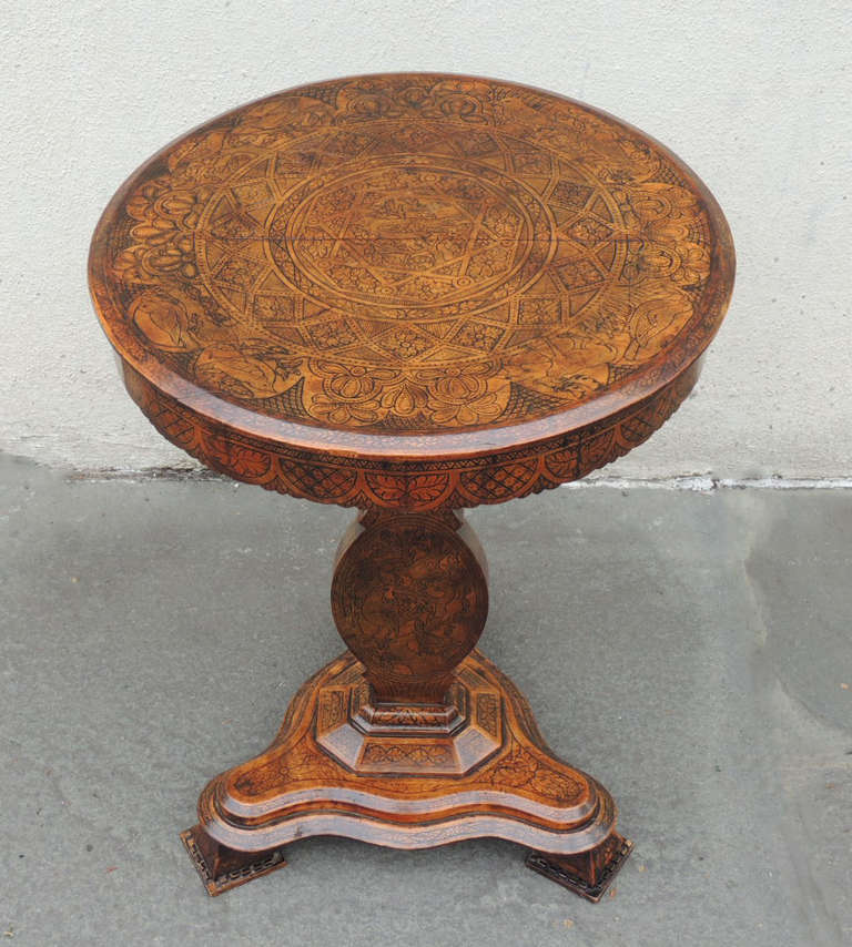 This table was made in Spain during the first half of the 19th century, and is covered with intricate pen work featuring flora, fauna, and geometric designs. The top tilts for storage and the table stands on a tripod base with draped feet. This